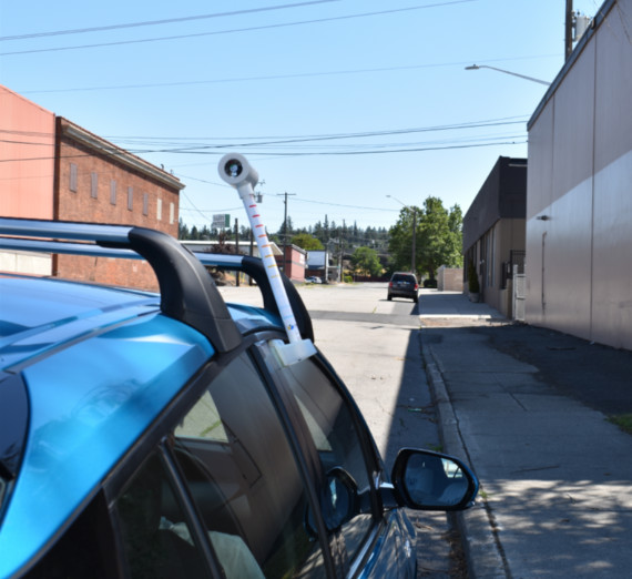 two people hoist a large tree into a hole next to a trail